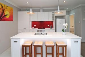 a kitchen with white cabinets and a sink and stools at Country Living on Raynes Road in Hamilton