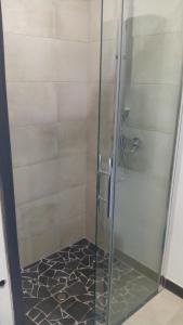 a shower with a glass door and a tile floor at Pigeonnier in Vic-le-Comte