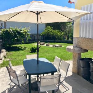 une table et des chaises bleues avec un parasol dans l'établissement CASA Campelo - Playas de Pinténs - HIO - Ría de Aldán - CANGAS, à Hio