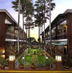 a building with a courtyard with palm trees and a fountain at Kebun Teh Wonosari Rollaas Hotel & Resort in Malang