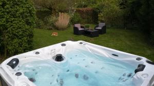 eine Whirlpool-Badewanne im Hof mit zwei Stühlen in der Unterkunft Monts et Merveilles in Godewaersvelde