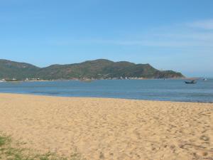 a sandy beach with a boat in the water at Mai Tra Hotel in Quy Nhon