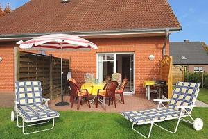 eine Terrasse mit einem Tisch, Stühlen und einem Sonnenschirm in der Unterkunft Ferienhaus "Nico" in Dankern