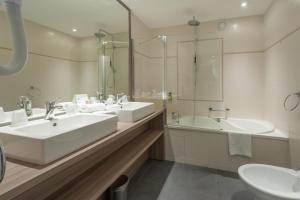 a bathroom with two sinks and a shower and a tub at Hotel & Spa Radiana in La Léchère