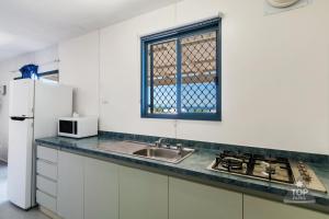 a kitchen with a stove top oven and a sink at Denham Seaside Caravan Park in Denham