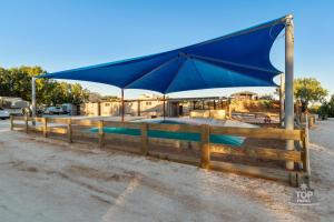 a swimming pool with a blue umbrella over a fence at Tasman Holiday Parks - Denham Seaside in Denham