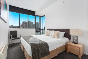 a bedroom with a large bed with a chair and a window at Docklands Private Collection - NEWQUAY in Melbourne