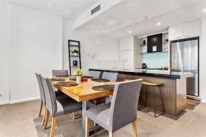 a kitchen and dining room with a wooden table and chairs at Docklands Private Collection - NEWQUAY in Melbourne