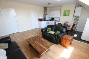 a living room with a black leather couch and a table at MARLEY MANSIONs APARTMENTS - KING ST REF : 10/3 in Wallasey