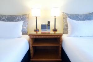a room with two beds and a nightstand with two lamps at Soho Brisbane in Brisbane