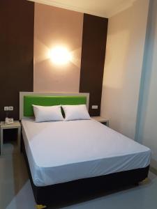 a bedroom with a white bed with a green headboard at Ethan Hotel Kelapa Gading in Jakarta
