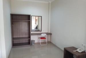 a room with a chair and a desk and a mirror at Ethan Hotel Kelapa Gading in Jakarta