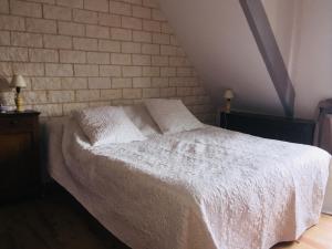 a bedroom with a white bed with a brick wall at Chambres de Scavet in Tréguier