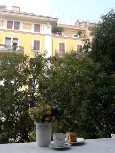 a cup of coffee and a vase with flowers on a table at Il Mondo Di Amelia in Rome