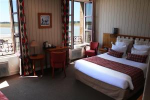 a hotel room with a large bed and windows at La Mère Poulard in Le Mont Saint Michel