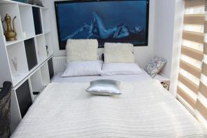 a small bedroom with a white bed with pillows at Art apartman in Kakanj