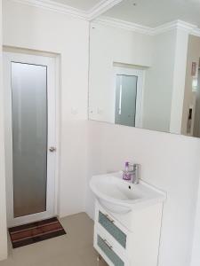 a white bathroom with a sink and a mirror at Ethan Hotel Kelapa Gading in Jakarta