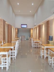 a dining room with wooden tables and white chairs at Ethan Hotel Kelapa Gading in Jakarta