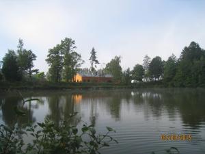 Blick auf einen See mit einem Haus im Hintergrund in der Unterkunft Florennes Gîte neuf 150 M2 devant un grand lac privé de 2 hectares poissonneux au milieu des bois in Florennes
