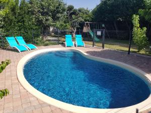 una piscina con sillas azules y un columpio en Villa La Milouyette, en Peyriac-Minervois