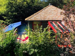 艾瓦耶的住宿－Vintage Chalet in Sougn Remouchamps near Forest，一个带遮阳伞和椅子的小房子