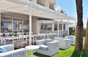 a patio with white wicker chairs and tables at Sol Puerto Marina in Torremolinos