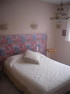 a bedroom with a white bed with a floral headboard at Domaine de la Pendule in Issel