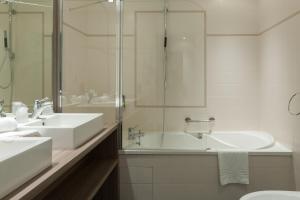 a white bathroom with two sinks and a shower at Hotel & Spa Radiana in La Léchère