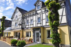 ein weißes und gelbes Haus mit einem Baum in der Unterkunft Hotel Garni-Tell in Siegen