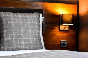 a bed with a pillow and a light on a wall at Dalziel Park Hotel in Motherwell