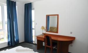 Habitación con escritorio con espejo y cortinas azules. en Hotel Veleka, en Chernomorets