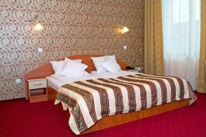 a hotel room with a bed with a striped blanket at Hotel Xemar in Arad