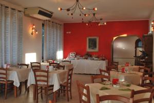 a dining room with white tables and red walls at Albergo Smeraldo in Castelnuovo Magra