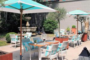 a patio area with tables, chairs and umbrellas at Hotel Barsey by Warwick in Brussels