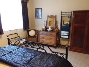 a bedroom with a bed and a dresser and a mirror at Cornwall Cottage in Cambridge