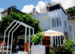 a white building with an umbrella and a building at Mayhow Donghe in Donghe