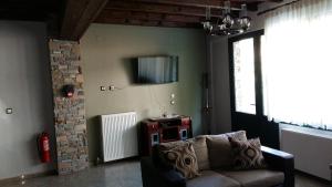 a living room with a couch and a tv on the wall at Guesthouse Oneiro in Kato Loutraki