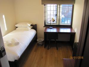 a bedroom with a desk and a bed and a window at West Court- Jesus College in Cambridge