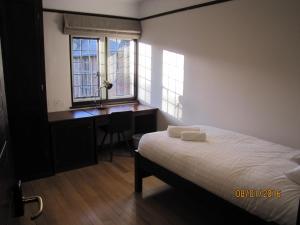 a bedroom with a bed and a desk and windows at West Court- Jesus College in Cambridge