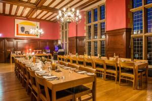 a large dining room with long tables and a chandelier at West Court- Jesus College in Cambridge
