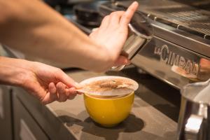 a person is making a cup of coffee at West Court- Jesus College in Cambridge