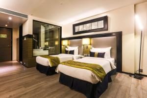 a hotel room with two beds and a bathroom at The Empresa Hotel in Mumbai