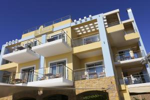 a yellow building with balconies and a blue sky at Almira Hotel in Arkoudi