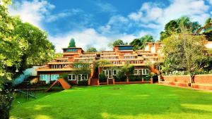 a large building with a green lawn in front of it at Kodai Resort Hotel, Kodaikanal in Kodaikānāl