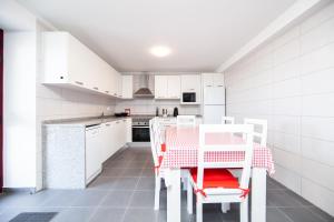 a kitchen with white cabinets and a table and chairs at Melo's Place in Madalena
