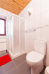 a white bathroom with a toilet and a shower at Melo's Place in Madalena