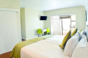 1 dormitorio con 1 cama blanca grande con almohadas amarillas en Small Bay Guest House en Bloubergstrand