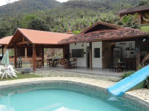 a house with a pool in front of a house at Pousada Chácara do Rio in Lumiar