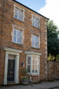 una casa in mattoni con finestre bianche e una porta di The Hollies Bed and Breakfast a Uppingham