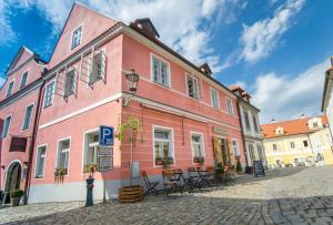 een roze gebouw met tafels en stoelen in een straat bij Hotel Latrán in Český Krumlov